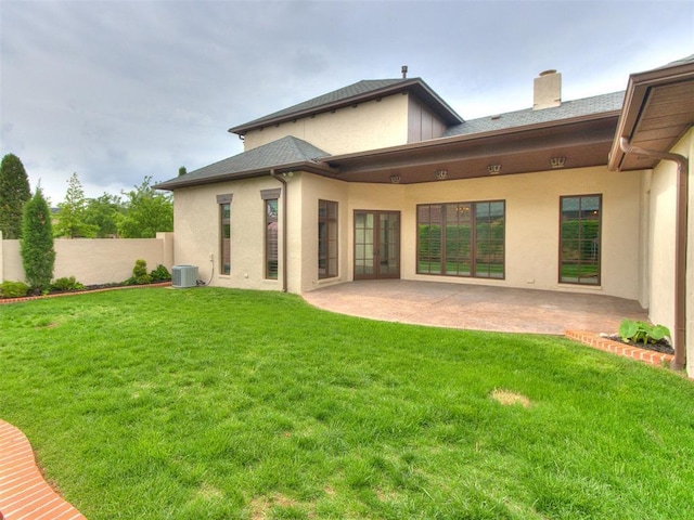 back of property with stucco siding, fence, and a yard