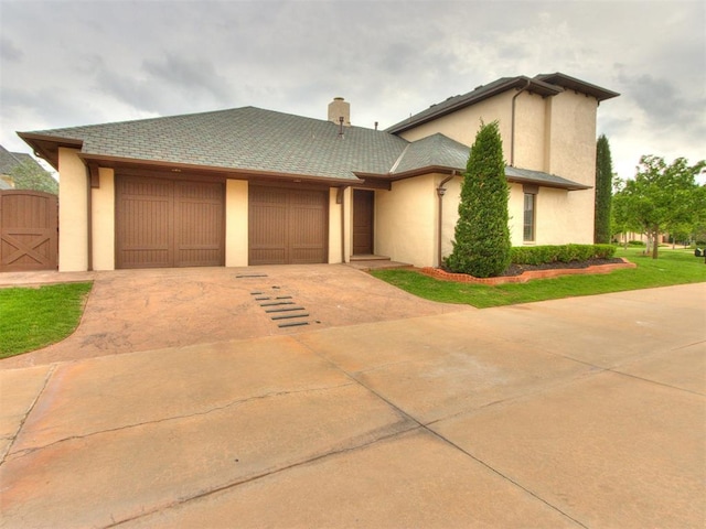 view of front facade with concrete driveway, stucco siding, a chimney, and a garage