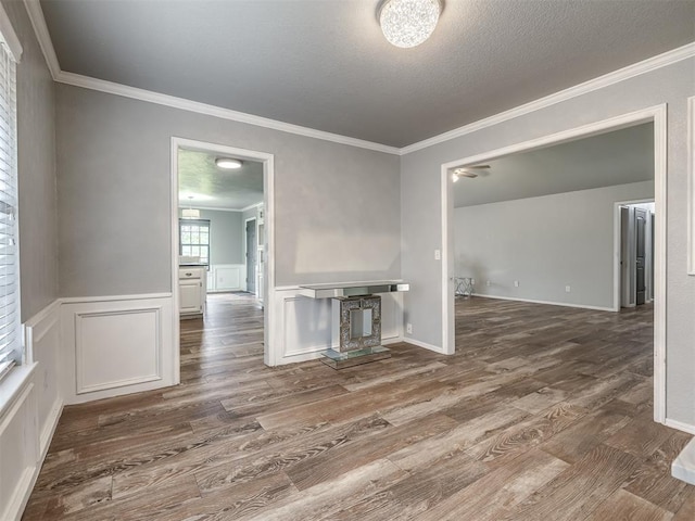 interior space featuring a decorative wall, ornamental molding, wainscoting, and wood finished floors