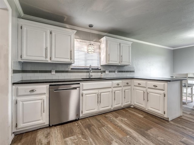kitchen with crown molding, dark countertops, white cabinets, a sink, and dishwasher