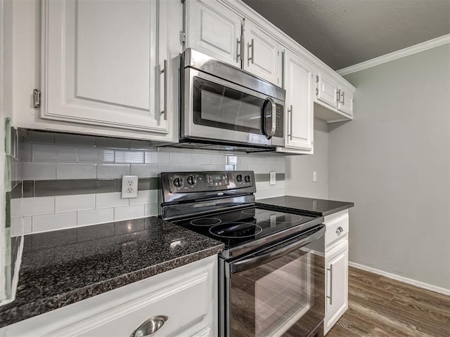 kitchen with electric range, stainless steel microwave, backsplash, and white cabinetry