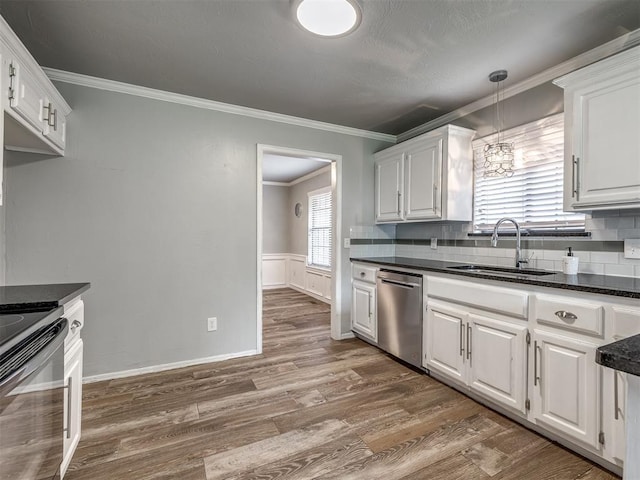 kitchen with black / electric stove, dark countertops, stainless steel dishwasher, a sink, and white cabinets