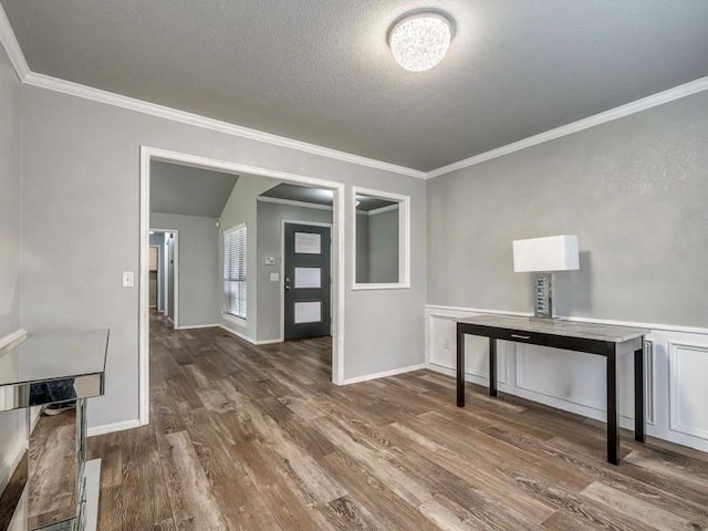 interior space featuring crown molding, baseboards, a textured ceiling, and wood finished floors