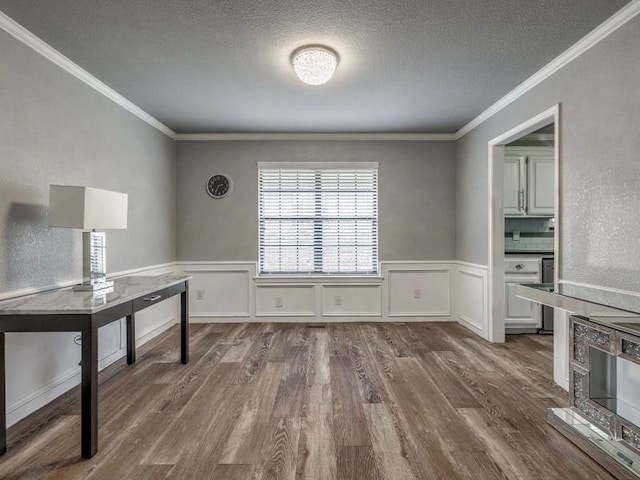 unfurnished dining area featuring crown molding, a textured ceiling, and dark wood finished floors