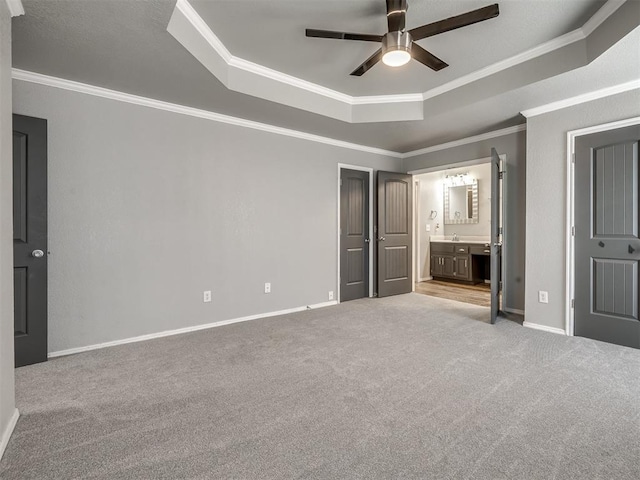 unfurnished bedroom with ornamental molding, a tray ceiling, and light carpet