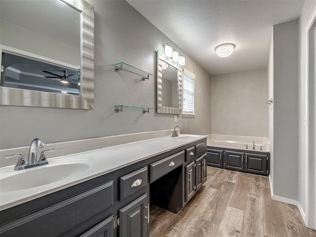 full bathroom featuring a sink, a bath, double vanity, and wood finished floors