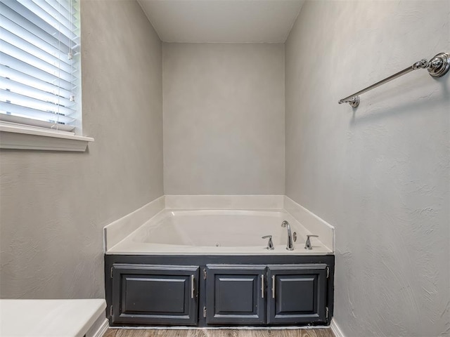 full bathroom with a bath and wood finished floors