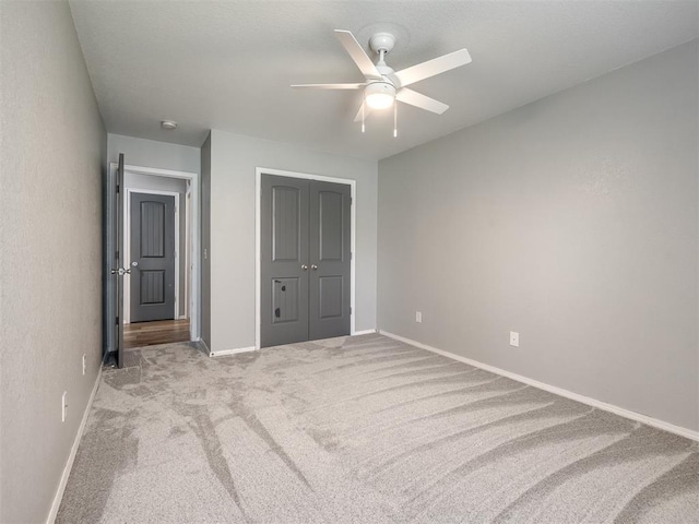 unfurnished bedroom with baseboards, carpet flooring, a ceiling fan, and a closet