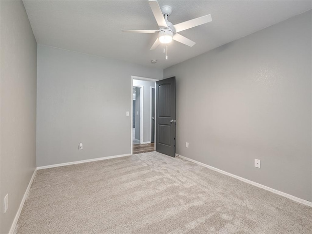 carpeted empty room featuring baseboards and ceiling fan