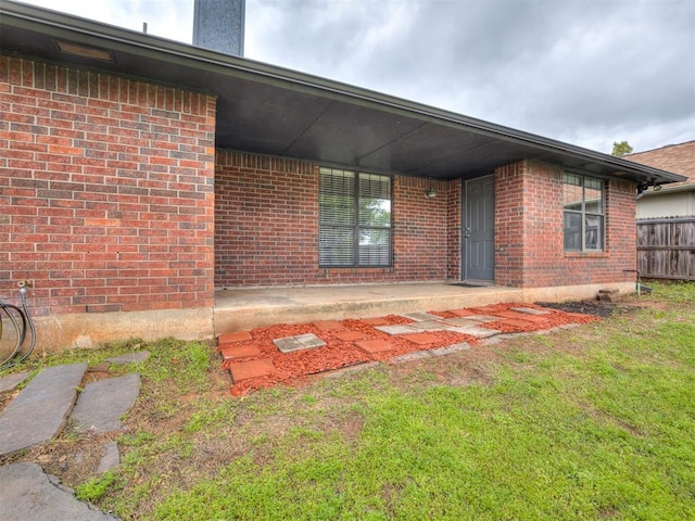 rear view of house with a lawn, brick siding, and fence