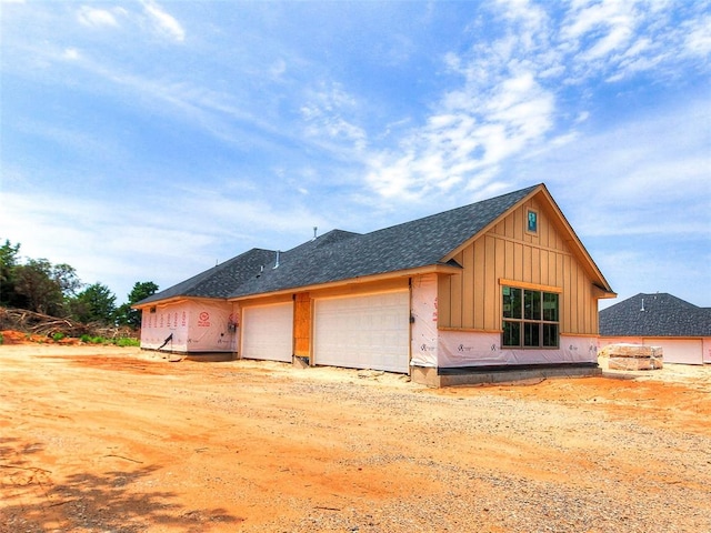 11673 Ward Rd, Edmond, OK 73034 - view of home's exterior featuring board and batten siding, an attached garage, and roof with shingles