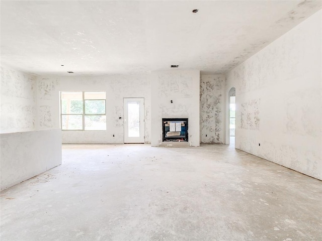 11673 Ward Rd, Edmond, OK 73034 - unfurnished living room with unfinished concrete flooring, a multi sided fireplace, and arched walkways