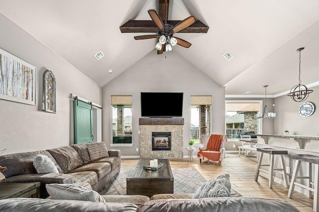 living area featuring visible vents, a healthy amount of sunlight, ceiling fan with notable chandelier, and light wood-type flooring