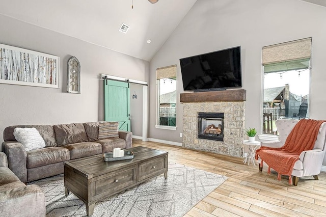 living area with visible vents, a barn door, wood finished floors, and a wealth of natural light