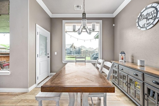 dining room with an inviting chandelier, baseboards, crown molding, and visible vents