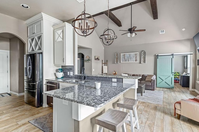 kitchen with a sink, arched walkways, stainless steel appliances, and open floor plan