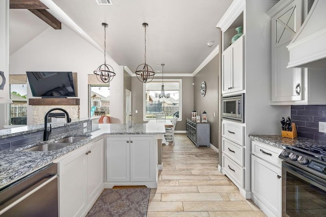 kitchen featuring a sink, premium range hood, light stone counters, a chandelier, and stainless steel appliances