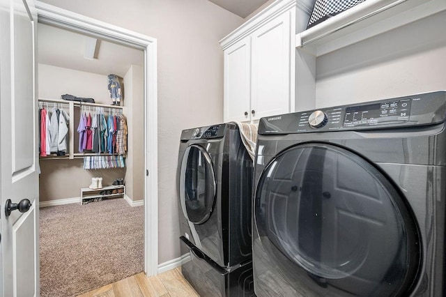 clothes washing area with washer and dryer, baseboards, light wood finished floors, and cabinet space
