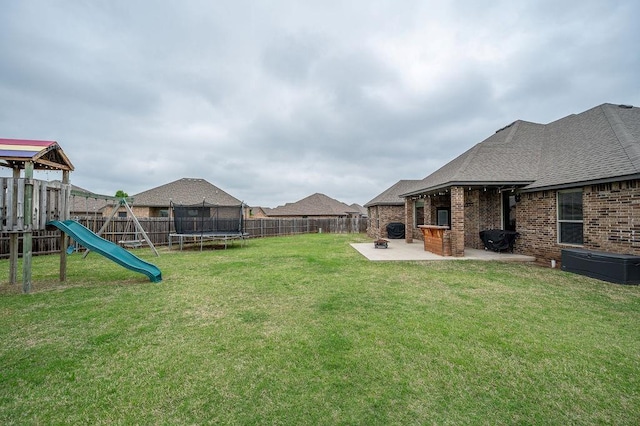 view of yard with a fenced backyard, a trampoline, a patio area, and a playground