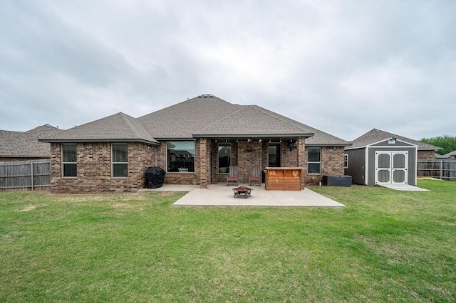 rear view of property with a storage shed, brick siding, a fenced backyard, an outdoor fire pit, and a patio