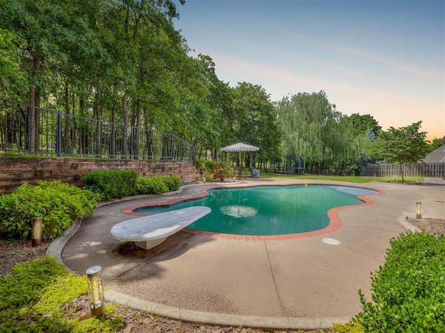 3125 Cumberland Dr, Edmond, OK 73034 - pool at dusk featuring a fenced backyard and a patio