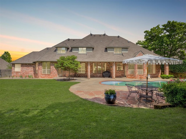 3125 Cumberland Dr, Edmond, OK 73034 - back of house at dusk featuring a patio, brick siding, roof with shingles, and a gazebo