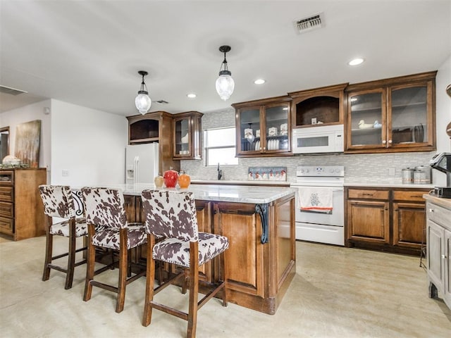 kitchen with backsplash, a kitchen island, white appliances, and visible vents