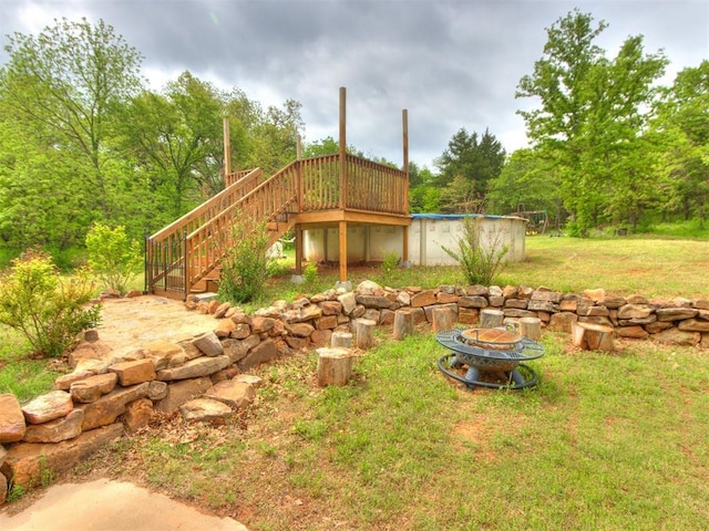view of yard featuring stairs, an outdoor fire pit, a covered pool, and a deck