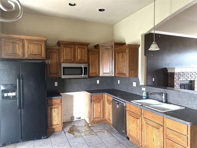 kitchen featuring a sink, appliances with stainless steel finishes, hanging light fixtures, and dark countertops