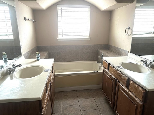 full bath featuring tile patterned floors, two vanities, a sink, and a garden tub