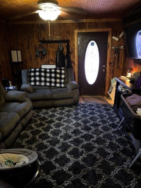living room with a ceiling fan, carpet, wooden walls, and wood ceiling