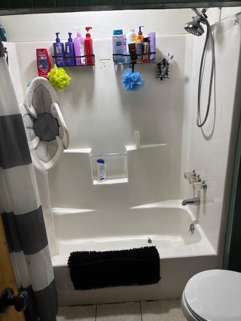full bathroom with shower / bath combo with shower curtain, toilet, and tile patterned flooring