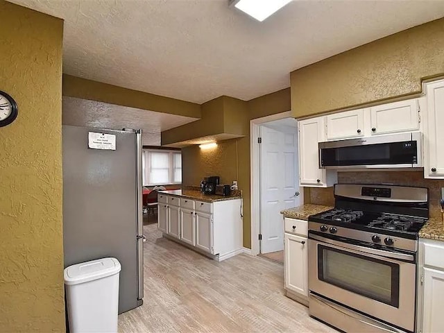 1904 NW Euclid Ave, Lawton, OK 73507 - kitchen featuring white cabinetry, a textured wall, appliances with stainless steel finishes, and light wood-type flooring