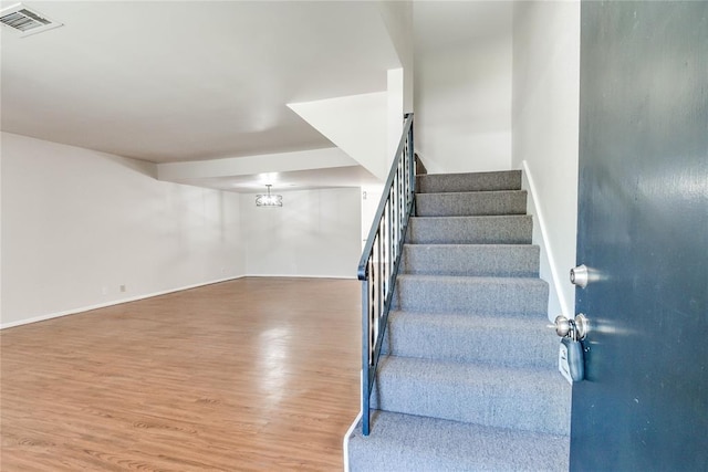 stairway featuring visible vents, baseboards, and wood finished floors