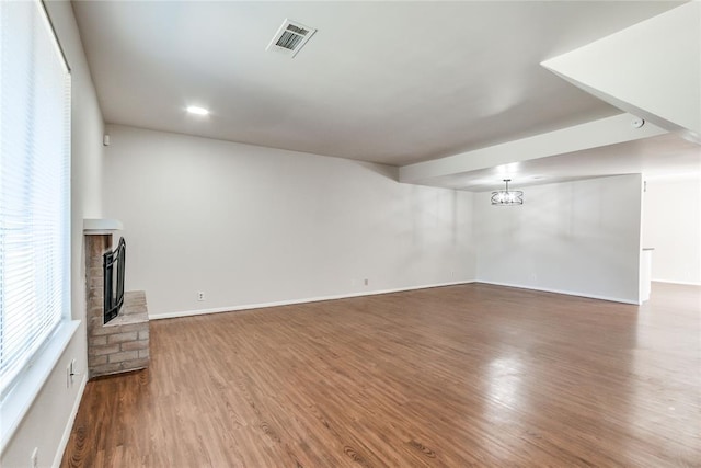 unfurnished living room featuring baseboards, visible vents, dark wood-style floors, and a fireplace