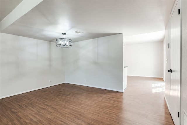 interior space with baseboards, wood finished floors, a notable chandelier, and visible vents