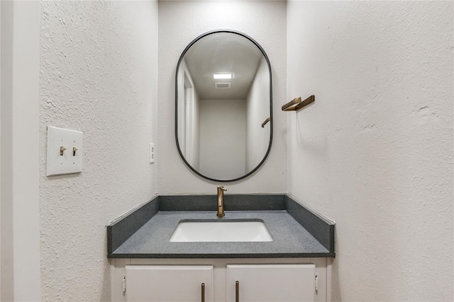bathroom with vanity, a textured wall, and visible vents