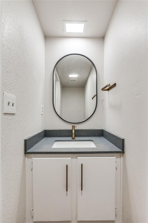 bathroom with vanity and a textured wall