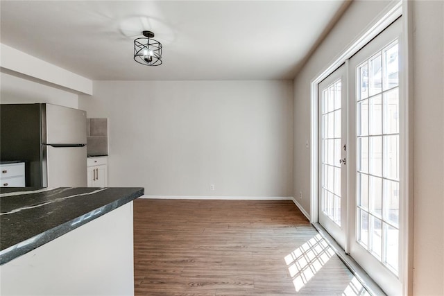 kitchen with baseboards, freestanding refrigerator, wood finished floors, and dark countertops