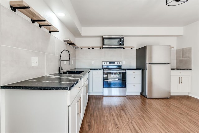 kitchen with backsplash, open shelves, a sink, stainless steel appliances, and white cabinetry