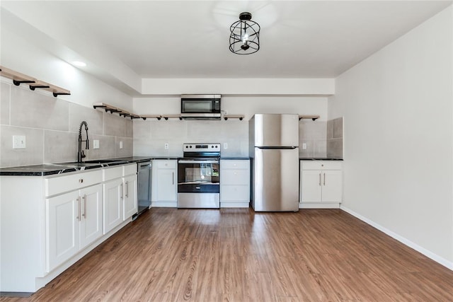 kitchen with decorative backsplash, dark countertops, open shelves, a sink, and stainless steel appliances