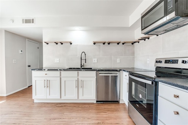kitchen with open shelves, appliances with stainless steel finishes, a sink, decorative backsplash, and visible vents