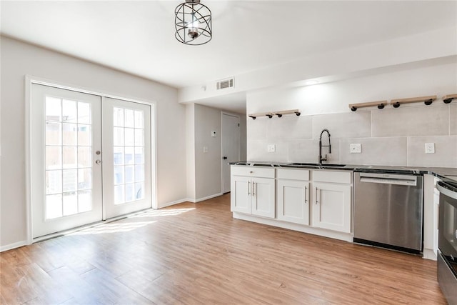 kitchen with stainless steel dishwasher, open shelves, visible vents, dark countertops, and a sink