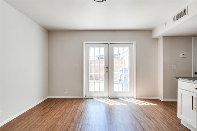 interior space with baseboards, visible vents, french doors, and light wood-style floors