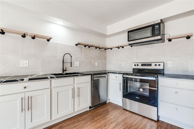 kitchen with dark countertops, appliances with stainless steel finishes, decorative backsplash, and a sink