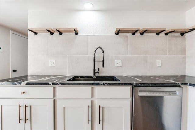 kitchen with tasteful backsplash, stainless steel dishwasher, a sink, dark stone counters, and white cabinetry