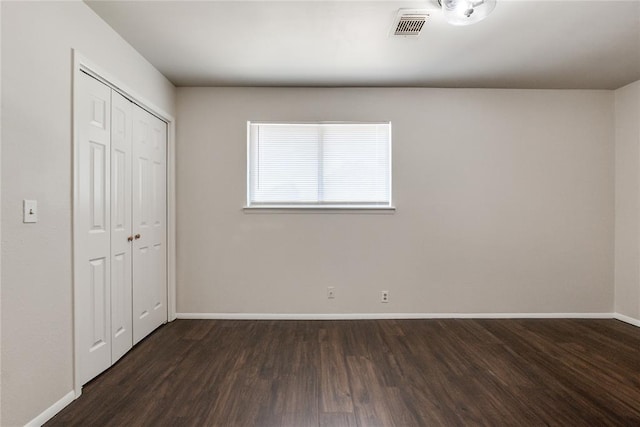 unfurnished bedroom featuring baseboards, a closet, wood finished floors, and visible vents