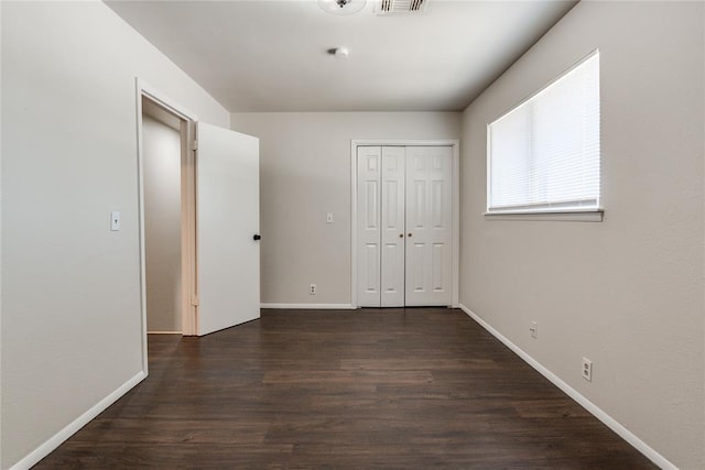 unfurnished bedroom featuring dark wood-type flooring, baseboards, and visible vents