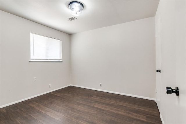 spare room with baseboards, dark wood-style flooring, and visible vents