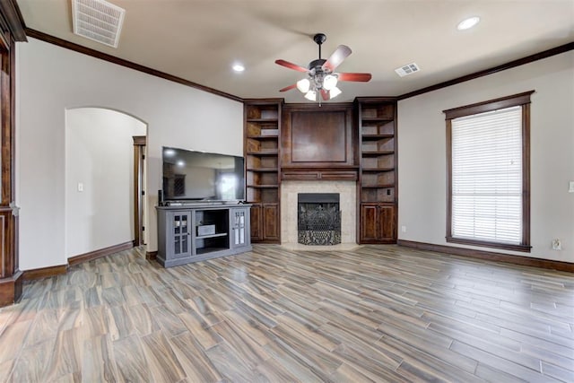 unfurnished living room with visible vents, ornamental molding, a ceiling fan, and arched walkways